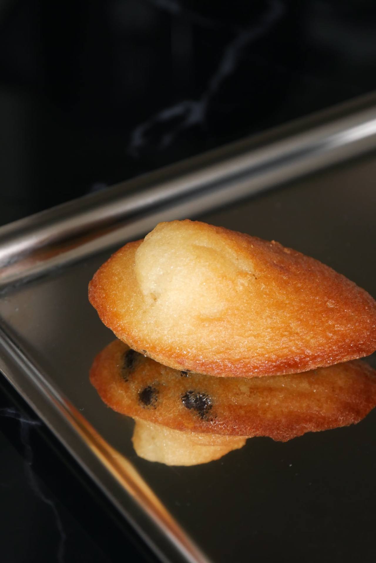 Madeleine dorée sur un plateau en inox, reflet d’une madeleine aux pépites de chocolat